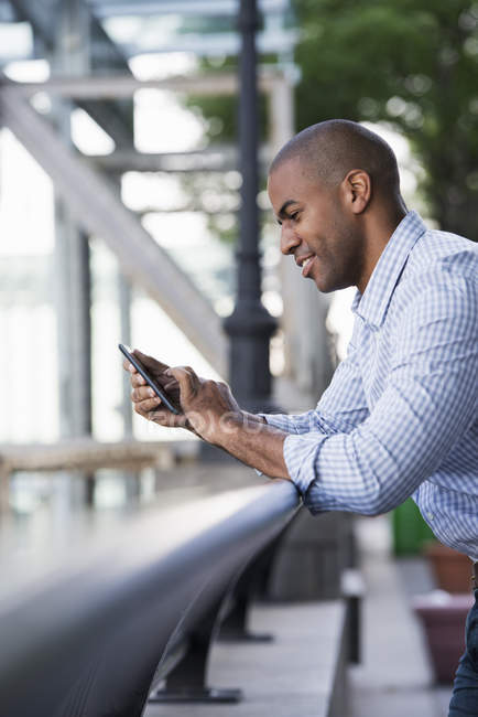 Homem adulto médio na camisa verificando smartphone, vista lateral . — Fotografia de Stock