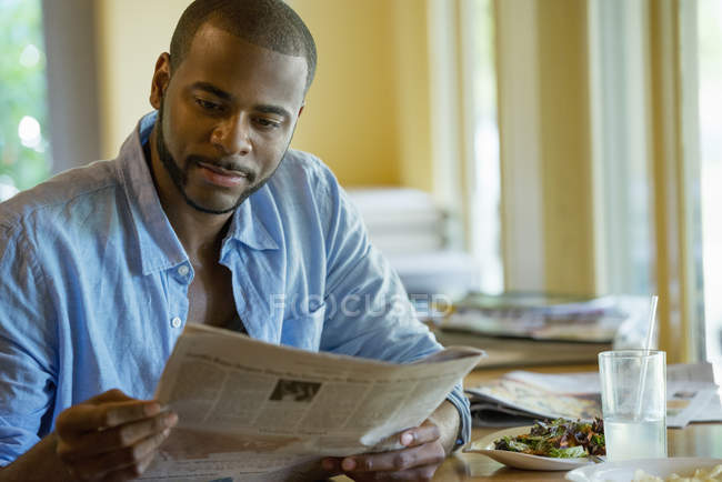 Man sitting in cafe and reading newspaper. — Stock Photo