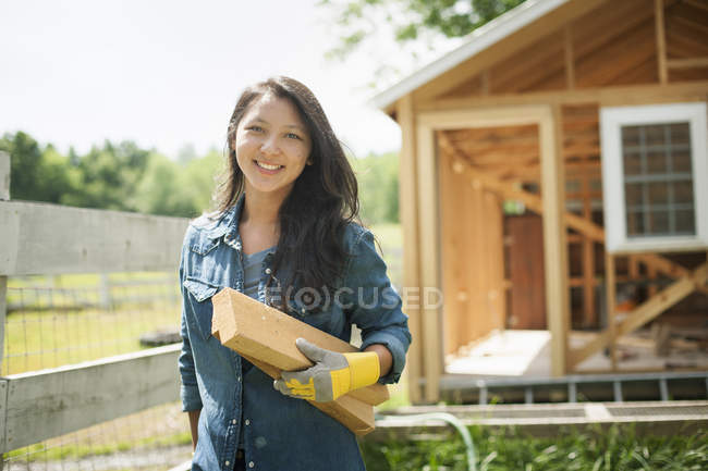 Woman carrying wooden logs at traditional farm in countryside. — Stock Photo