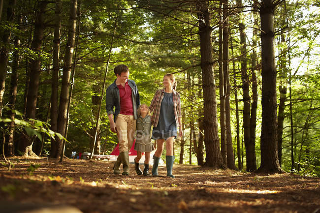 Familia con hija caminando en el bosque en luz suave . - foto de stock