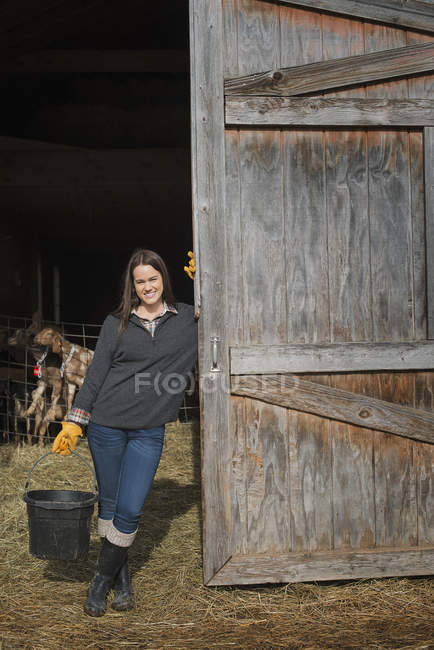 Jungbäuerin hält Eimer mit Wasser in Bauernhof. — Stockfoto