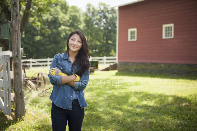 Young woman standing in front of traditional farm house in countryside. — Stock Photo