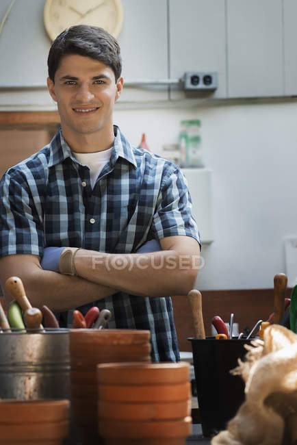 Young man in potting shed by work bench at organic farm. — Stock Photo