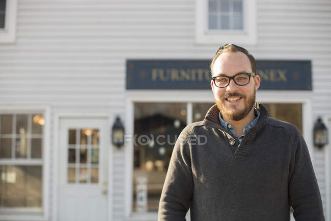 Man standing in front of antique store sign on street. — Stock Photo