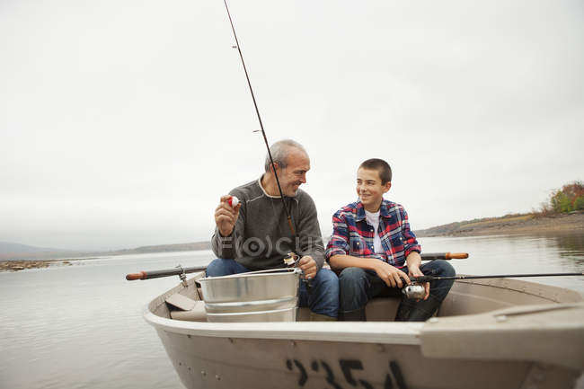 Reifen Mann und teen junge sitzen und fischen aus Boot. — Stockfoto