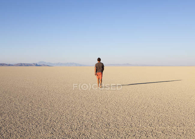 Mann läuft durch flache Wüstenlandschaft — Stockfoto