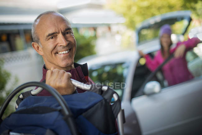 Hombre sosteniendo el bolso y la mujer de pie junto a la puerta del coche abierto mientras sale para el viaje . - foto de stock