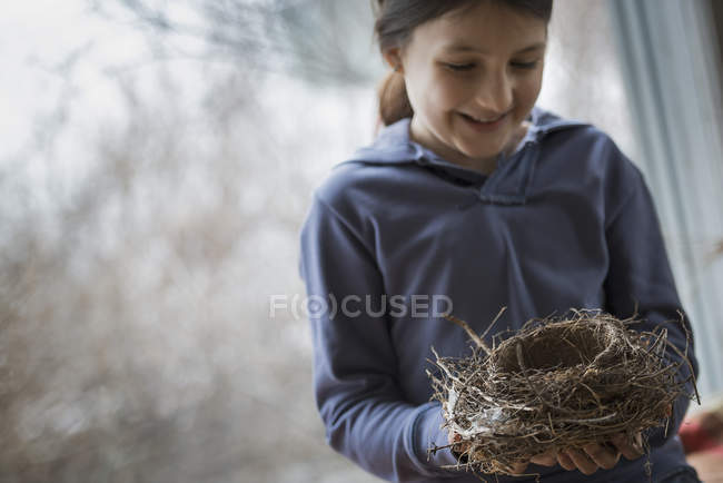 Vorpubertierendes Mädchen hält Vogelnest aus Zweigen und Blättern. — Stockfoto