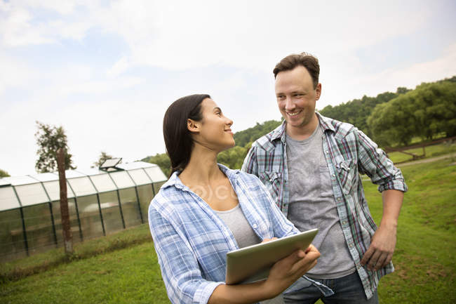 Мужчина и женщина используют цифровой планшет на органической ферме . — стоковое фото