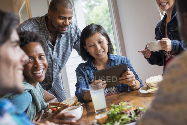 Groupe de personnes déjeunant et utilisant une tablette numérique lors d'une réunion dans un café
. — Photo de stock