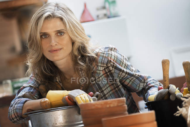 Jovem mulher em vaso galpão pelo banco de trabalho na fazenda orgânica . — Fotografia de Stock