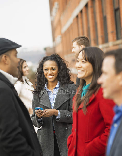 Woman standing on street with mobile phone and group of people in New York, USA — Stock Photo