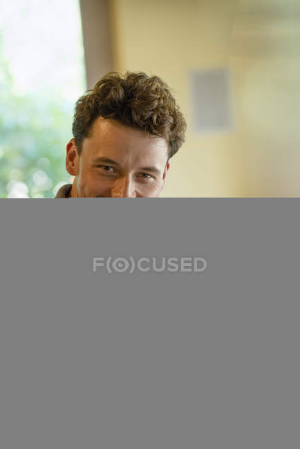 Young man smiling and using digital tablet indoors. — Stock Photo