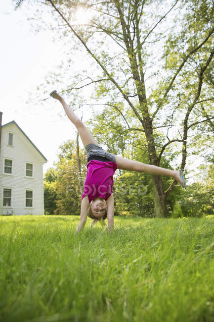 Menina pré-adolescente cartwheeling no jardim verde da fazenda . — Fotografia de Stock