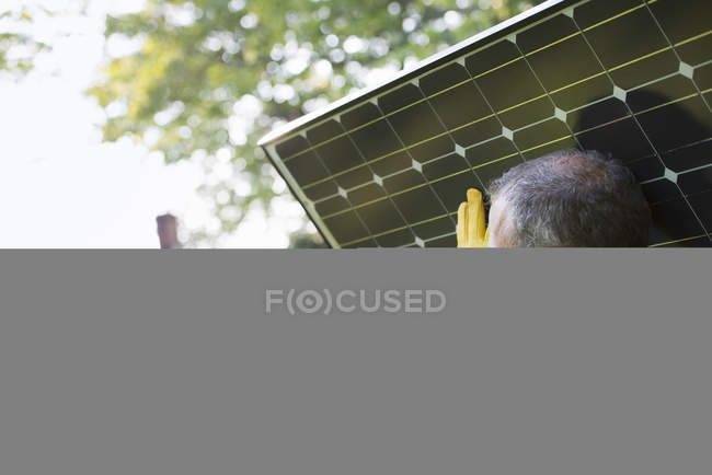 Hombre llevando panel solar hacia la construcción en el campo . - foto de stock