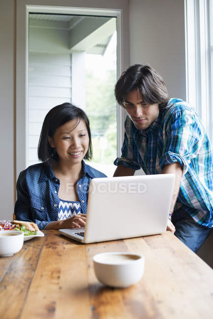 Jovem e mulher usando computador portátil no café . — Fotografia de Stock