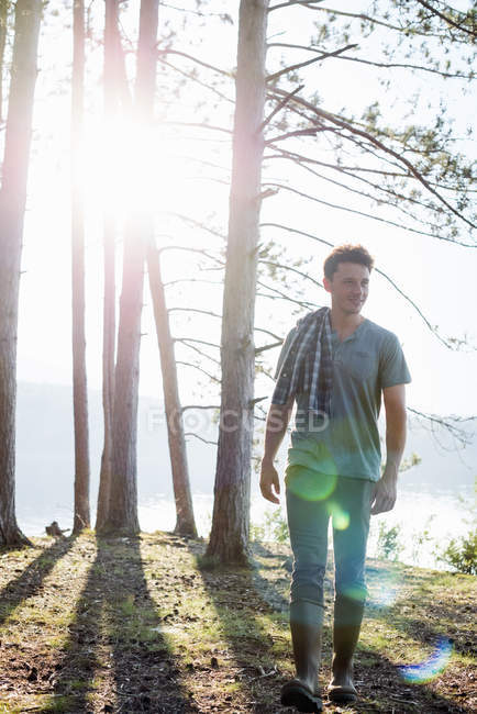 Vorderansicht eines Mannes, der am Seeufer im Wald spaziert. — Stockfoto