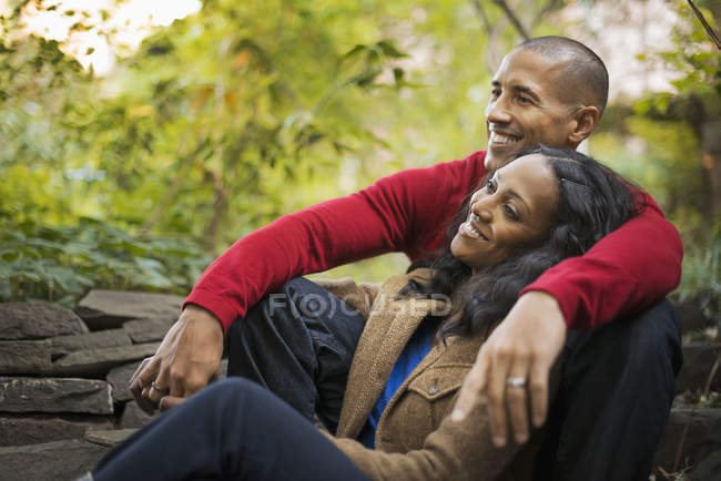Couple adulte moyen assis près des arbres dans le parc de la ville . — Photo de stock