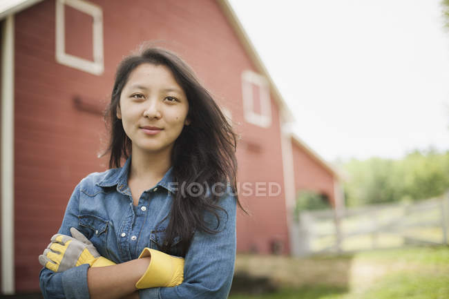Jovem mulher em pé na frente da casa de fazenda tradicional no campo . — Fotografia de Stock
