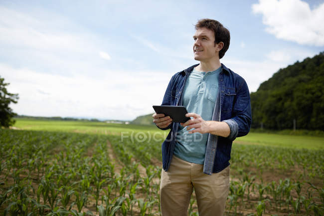 Giovane agricoltore che utilizza tablet digitale nel campo della coltivazione biologica di mais
. — Foto stock