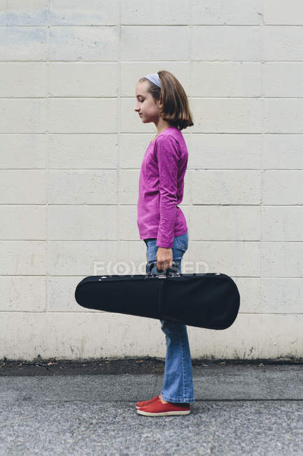 Vorpubertierendes Mädchen trägt Geigenkoffer auf städtischer Straße. — Stockfoto