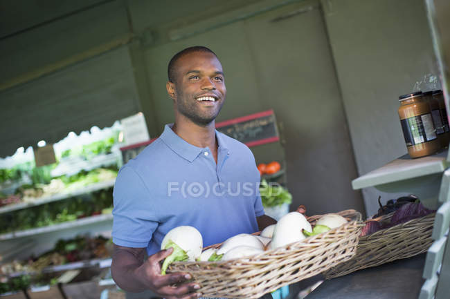Homem segurando cesta de berinjelas brancas em loja de fazenda orgânica . — Fotografia de Stock