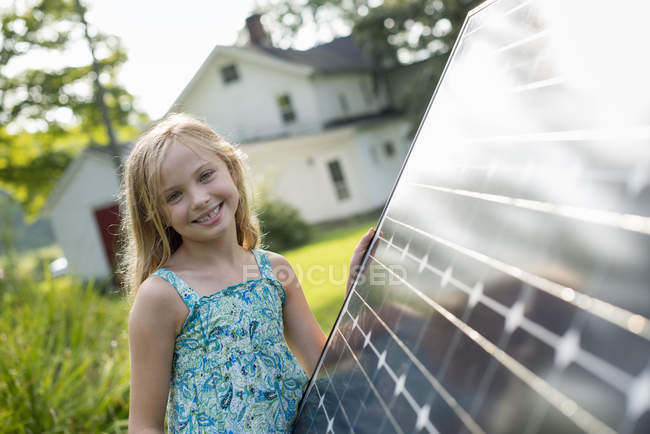 Menina idade elementar posando ao lado do painel solar no jardim da fazenda
. — Fotografia de Stock