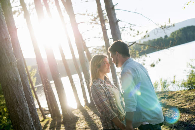 Couple debout face à face dans les bois sur la rive du lac forestier . — Photo de stock