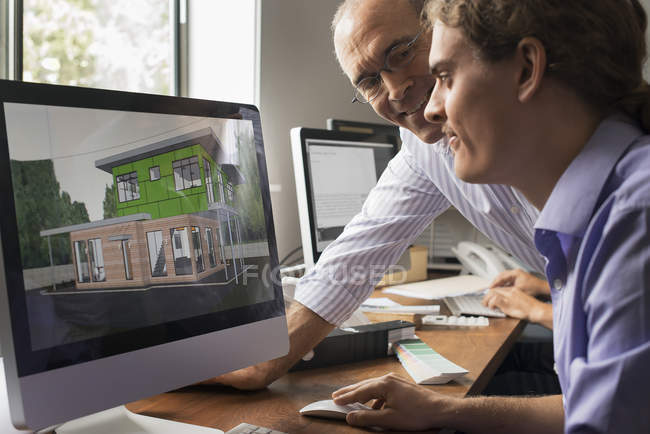 Architekten diskutieren grünes Bauprojekt auf Computerbildschirm im Büro. — Stockfoto