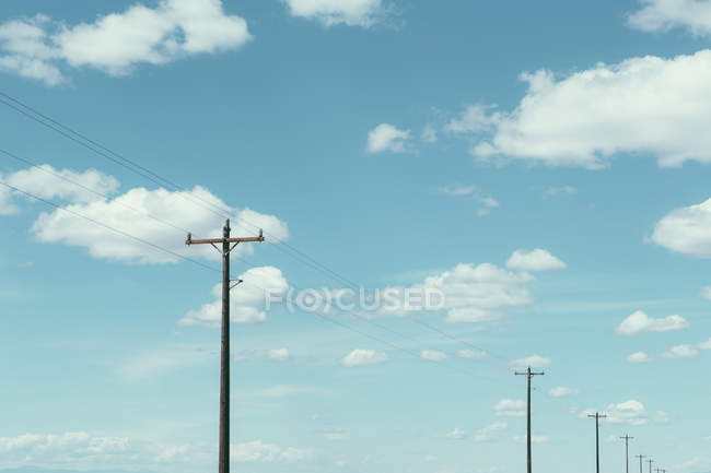 Телефонні стовпи, лінії електропередач і хмарне небо — стокове фото