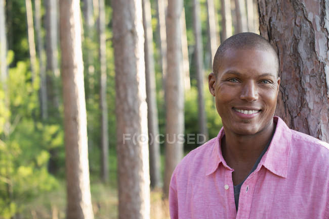 Afrikanisch-amerikanischer Mann im rosafarbenen Poloshirt steht im Wald. — Stockfoto