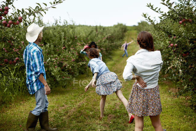 Jeunes hommes et jeunes femmes jetant des fruits sur la route rurale . — Photo de stock