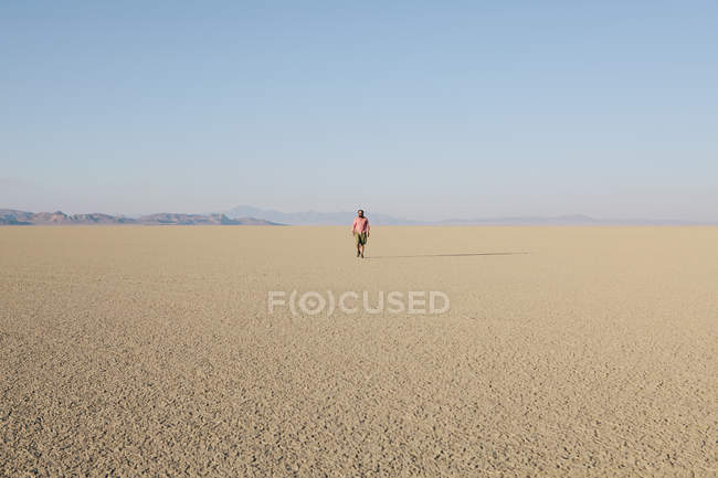 L'uomo cammina attraverso il paesaggio piatto del deserto — Foto stock