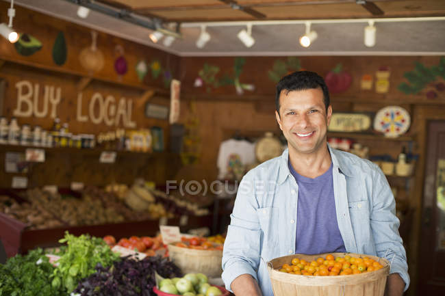Hombre sosteniendo tazón de tomates recién recogidos en tienda de agricultores . - foto de stock