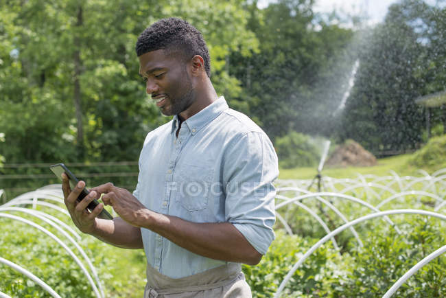 Junger Mann nutzt digitales Tablet in Bio-Gärtnerei. — Stockfoto