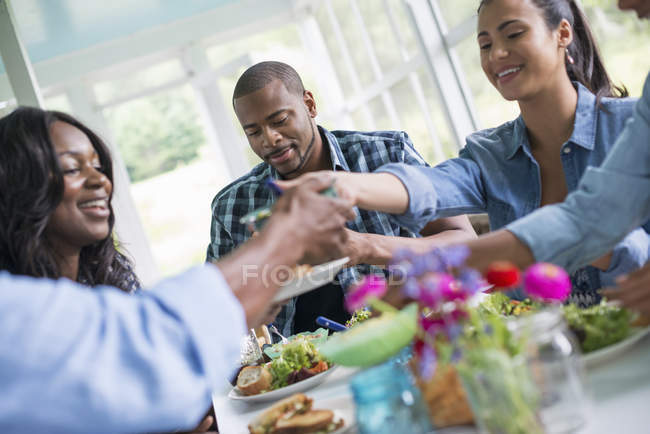 Grupo de mujeres y hombres compartiendo la cena en el interior de la casa de campo . - foto de stock
