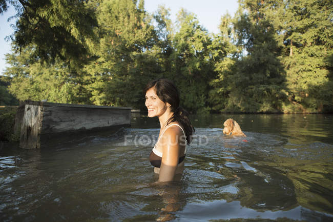 Mitte erwachsene Frau schwimmt mit Hund im Seewasser. — Stockfoto