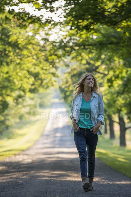 Frau läuft auf Landstraße in sonnigem Park. — Stockfoto