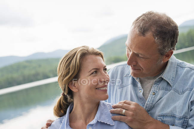 Couple d'âge mûr debout au bord du lac et se regardant . — Photo de stock