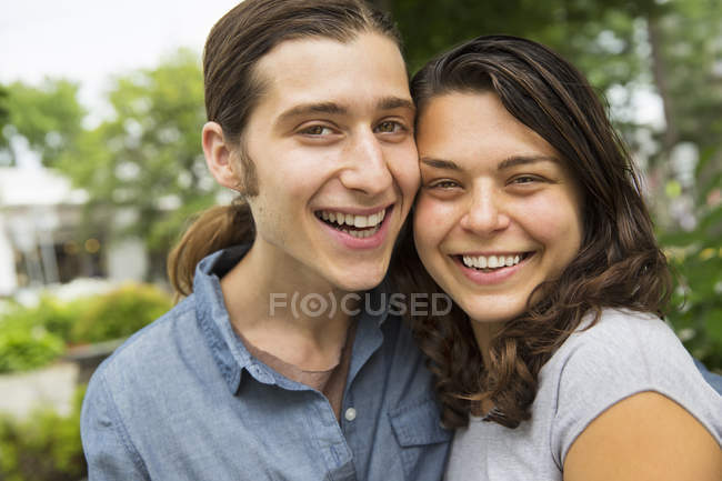 Молодая пара позирует щека к щеке на улице и улыбается — стоковое фото