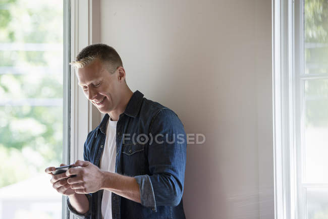 Человек, стоящий в углу и использующий смартфон . — стоковое фото