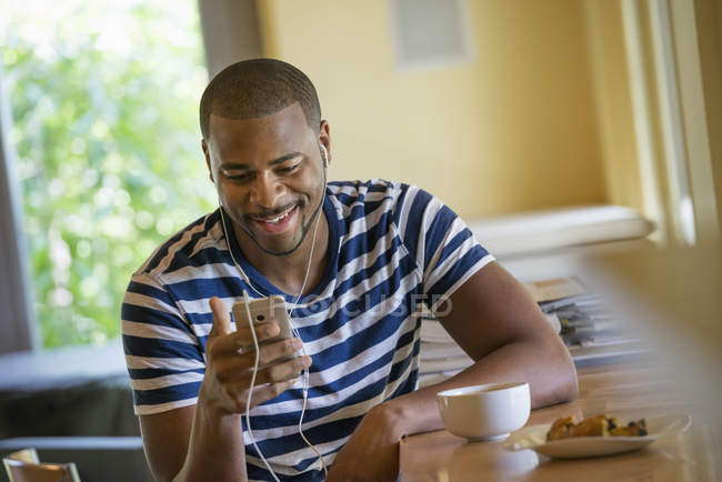 A man using a smart phone, or personal music player, wearing headphones. — Stock Photo