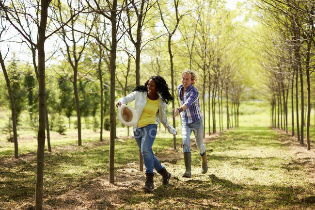 Young woman stealing hat and running away from young man in countryside. — Stock Photo
