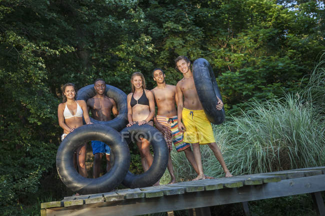 Giovani con galleggianti nuoto su pontile di legno vicino al lago naturale . — Foto stock