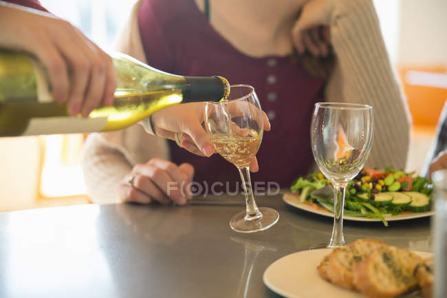 Молодий чоловік поливає вино в окуляри з жінкою в ресторані . — стокове фото