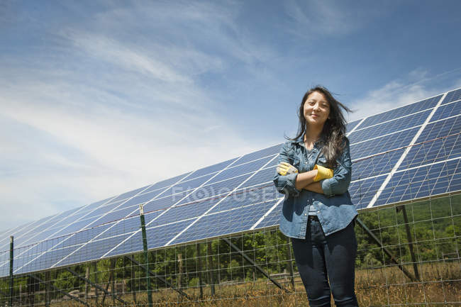 Giovane donna in piedi di fronte al pannello solare in fattoria in campagna . — Foto stock