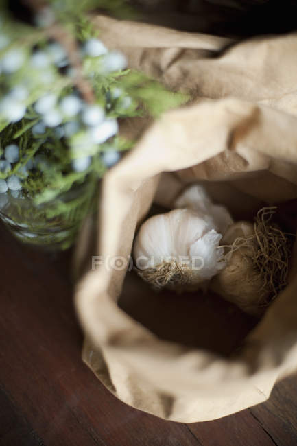 Lampadine di aglio in sacchetto di carta marrone con erbe e fiori blu . — Foto stock