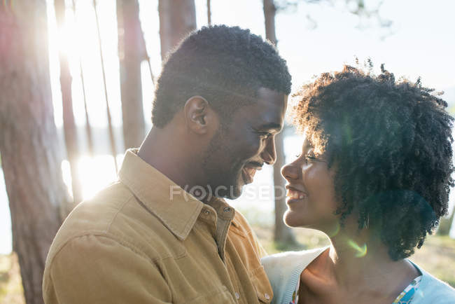 Happy couple standing face to face in sunny woodland. — Stock Photo