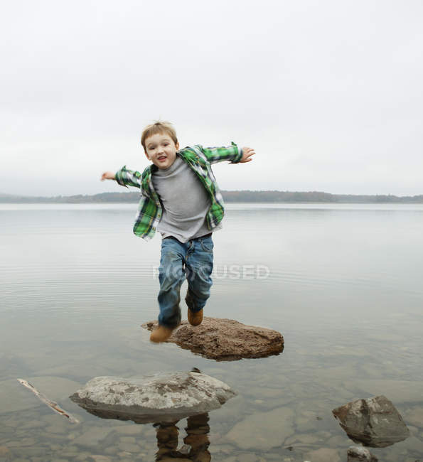 Junge im Grundschulalter springt über Trittsteine. — Stockfoto