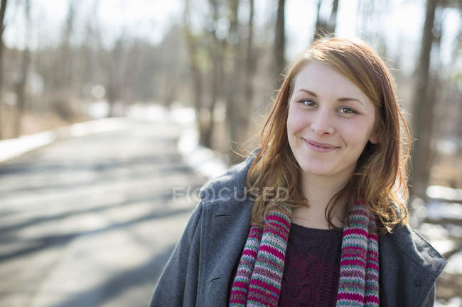 Jovem mulher em cachecol de malha na floresta no inverno . — Fotografia de Stock